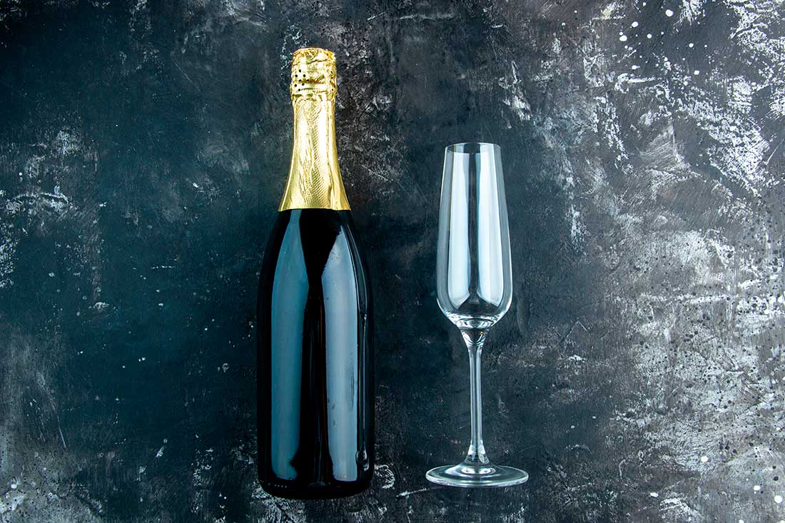 taça flute, um dos tipos de taça para champanhe, ao lado de uma garrafa