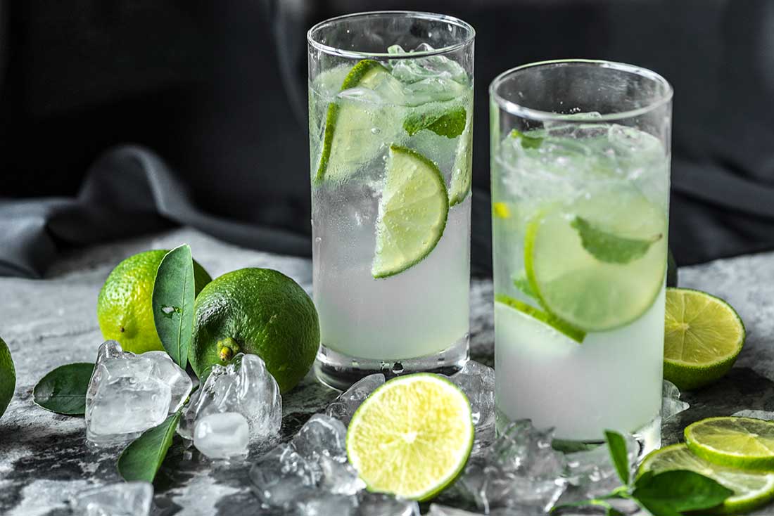 dois copos modelo highball cheios de limonada em uma mesa com outros elementos