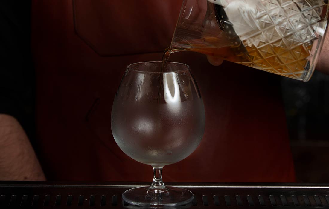 foto close de barman colocando cerveja em uma taça sniffer