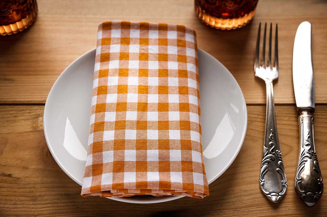 garfo de mesa ao lado de uma faca e um prato com guardanapo colorido
